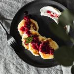 A tempting plate of pancakes topped with berry jam and sour cream, ideal for breakfast.